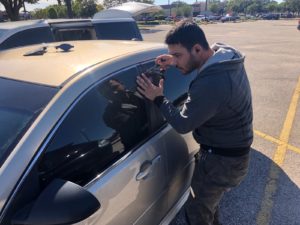 locksmith tech trying to open a car with his ACCESS tools services AIR JACK and pick tools in parking lot of walmart in Houston