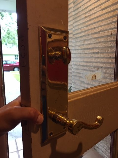 hand holding gold lock on residential door