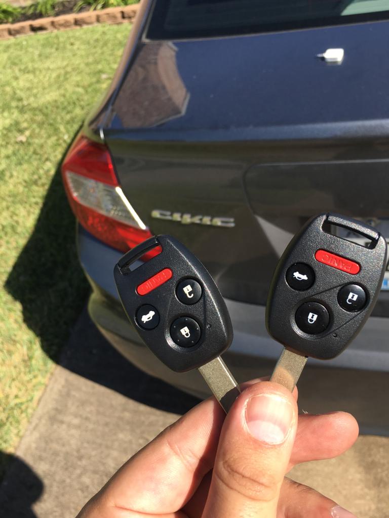 HAND holding two Honda replacement key automotive locksmith fobs next to a Honda civic car
