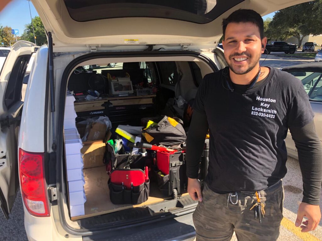 dan pinto owner of Houston key locksmith with uniform behind his mobile work car with locksmith tools, locks and keys