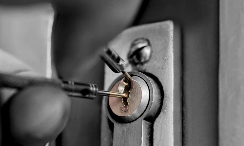 close-up hand holding pick tool trying to pick commercial business lock- one of the locksmith services skills that needed