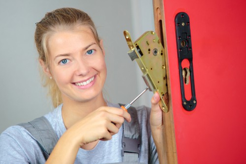 A women holding screw driver on commercial lock cylinder door