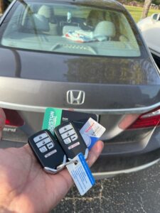 hand holding 2 remot smart key Honda with business card of Houston key locksmith
