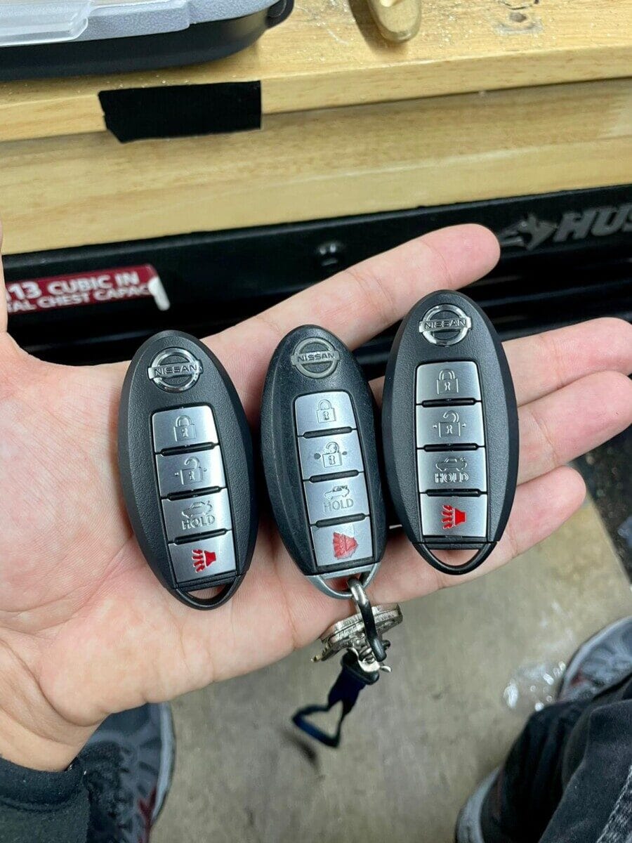Hand holding 3 Nissan/Infinti smart keys push to start key replacement