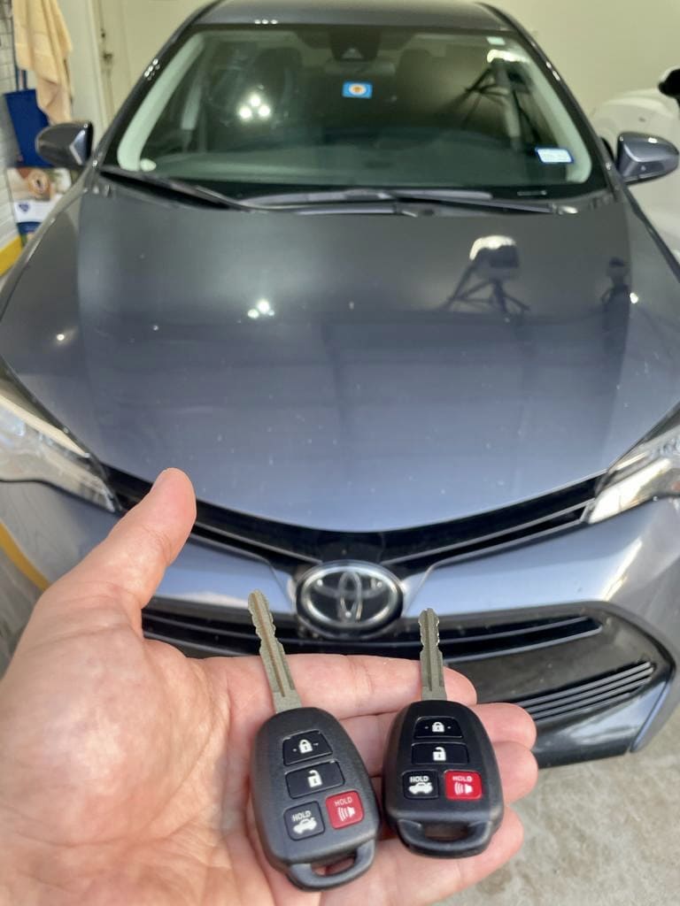 2 remote keys next to blue Toyota car