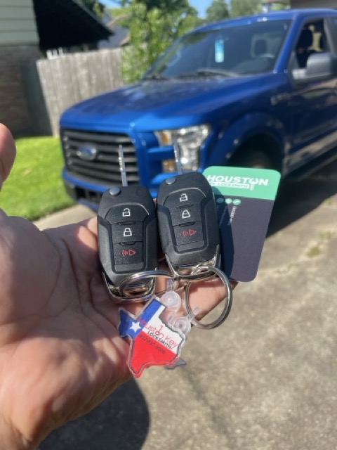 Hand holding a newly programmed Ford car key replacement for a Houston locksmith service.