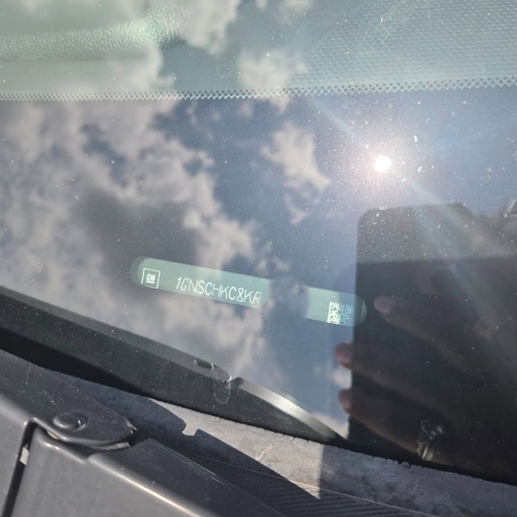 Looking through a car windshield with a sun reflecting off the glass to check the VIN number for a car key replacement