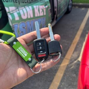 hand holding a set of transponder car keys and a spare ignition key