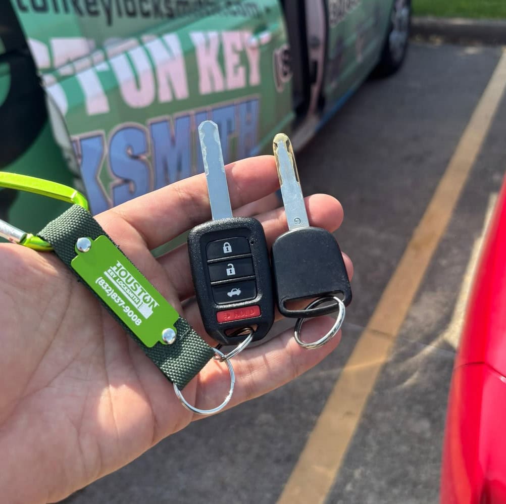 hand holding a set of transponder car keys and a spare ignition key
